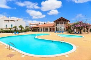 a swimming pool at a resort with chairs and a building at Guesthouse Le Châtelain in Santa Maria