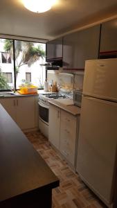 a kitchen with white appliances and a large window at Lujoso departamento in Quito