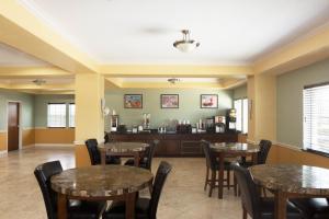 una sala da pranzo con tavoli e sedie e una cucina di Super 8 by Wyndham Rosenberg TX a Rosenberg