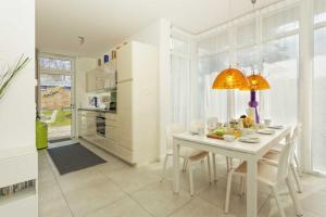 a white dining room with a white table and chairs at Lotsenstieg 15 in Ostseebad Karlshagen