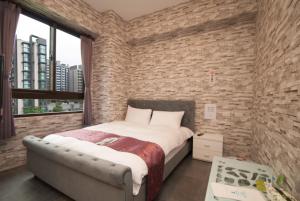ein Schlafzimmer mit einem großen Bett und einer Ziegelwand in der Unterkunft Yixiang Spring Travel in Jiaoxi