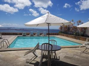 a table with an umbrella next to a swimming pool at Vitória Marina in Salvador