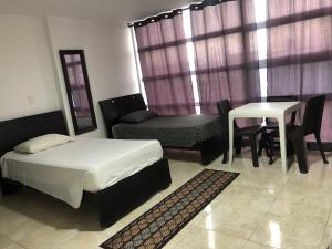 1 dormitorio con 1 cama, mesa y sillas en Hostal Central Beach, en San Andrés