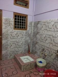 łazienka z toaletą w wyłożonej kafelkami ścianie w obiekcie VAMOOSETRAIL PASIGHAT(1) w Pasighat