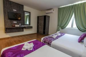 Salsa Resort Langkawi By Casa Loma في بانتايْ سينانج: غرفة مع سريرين مع ملاءات أرجوانية وتلفزيون