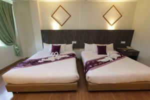 two beds in a room with purple and white sheets at Salsa Resort Langkawi By Casa Loma in Pantai Cenang