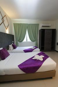a bedroom with two beds with purple sheets and a window at Salsa Resort Langkawi By Casa Loma in Pantai Cenang