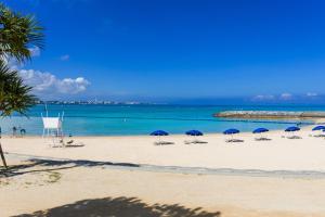 a beach with chairs and umbrellas and the ocean at Condominium Hotel Monpa in Chatan