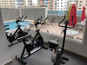 2 bicicletas estáticas en un gimnasio con vistas a la piscina en Torre Marbella apartamentos de 2 y 3 dormitorios, en Salinas