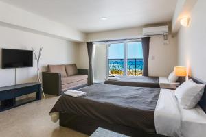 a bedroom with a bed and a couch and a television at Condominium Hotel Monpa in Chatan