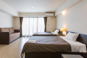 a hotel room with two beds and a couch at Condominium Hotel Monpa in Chatan