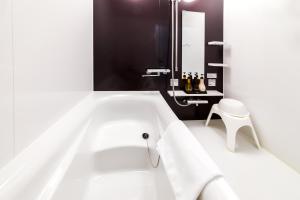 a bath tub with white towels and a stool in a bathroom at Condominium Hotel Monpa in Chatan
