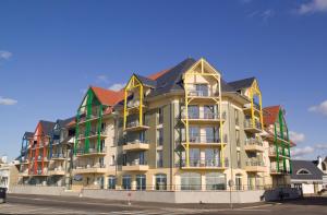 un gran edificio de apartamentos con techos amarillos y verdes en Madame Vacances Les Terrasses De La Plage en Cayeux-sur-Mer