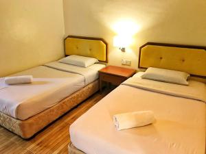 a room with two beds and a table with a lamp at Hotel Sri Raub in Raub