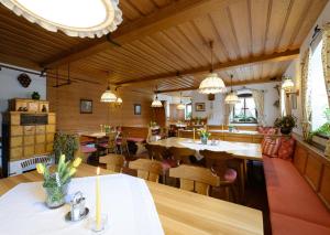 una sala da pranzo con tavoli, sedie e lampadari a braccio di Gasthof Mayrwirt a Saaldorf