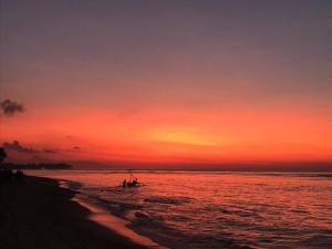 a boat on the beach at sunset at Meno Madia Bungalows in Gili Meno