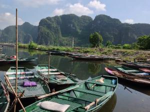 a group of boats in the water with mountains in the background at Tam Coc Eco House in Ninh Binh