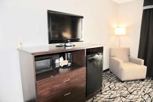 a hotel room with a television and a chair at Days Inn & Suites by Wyndham Wausau in Wausau