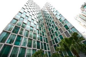 un edificio de cristal alto con palmeras delante en Soho Suites KLCC en Kuala Lumpur