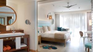 a bedroom with a bed and a sink and a mirror at C Mauritius in Belle Mare