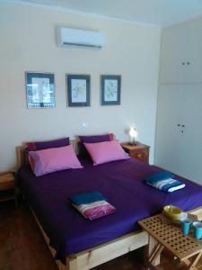 ein Schlafzimmer mit einem großen lila Bett mit rosa Kissen in der Unterkunft Mia's Atelier, Balcony to Acropolis in Athen
