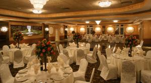 a banquet hall with white tables and white chairs at Meadowlands Plaza Hotel in Secaucus
