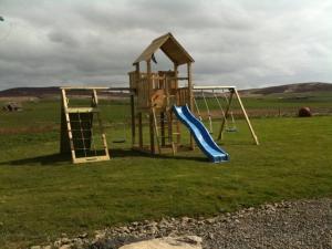 a playground with a slide in a field at Buxa Farm Chalets in Orphir