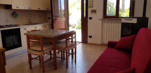 フォチェ・ヴァラーノにあるAppartamento Garganoのキッチン(テーブル、椅子、赤いソファ付)