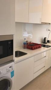 a white kitchen with a sink and a microwave at The Horizon Residences in Kuala Lumpur