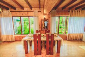 a dining room with a table and chairs and windows at Sarah Cottage Nuwara Eliya in Nuwara Eliya