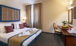 エルサレムにあるプリマ パレス ホテルのベッド2台とデスクが備わるホテルルームです。