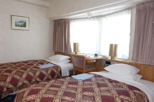 a hotel room with two beds and a desk at Hotel New Green Tsubame Sanjo in Sanjo