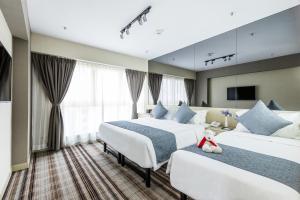 duas camas num quarto de hotel com um urso de peluche sentado na cama em Eco Tree Hotel Causeway Bay em Hong Kong