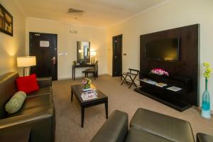 a living room with a couch and a flat screen tv at The Royal Riviera Hotel Doha in Doha