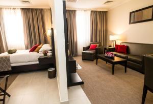 a hotel room with a bed and a living room at The Royal Riviera Hotel Doha in Doha
