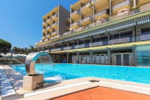 a swimming pool with a fountain in front of a building at Hotel Bellevue Et Mediterranée in Diano Marina