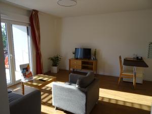 a living room with a couch and a table and a tv at Domitys Les Sarments Blonds in Montpellier