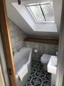 a bathroom with a tub and a toilet and a skylight at The Old Winery Loft in Edale