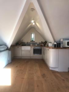 a large kitchen with white cabinets and a roof at The Old Winery Loft in Edale