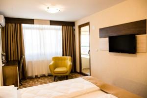 una camera d'albergo con letto, sedia e TV di Domino Residence a Zimandcuz