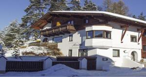 a building in the snow with trees in the background at Landhaus Almidyll in Seefeld in Tirol