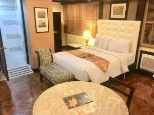 a hotel room with a bed and a table at Lourdes Suites in Manila