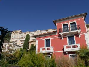 a red building with balconies in front of a large building at LOFT chic et moderne, déco industrielle in Beausoleil