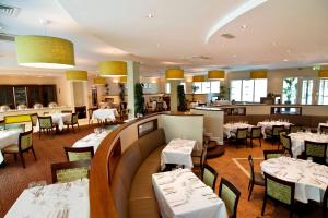 a restaurant with white tables and chairs and a bar at Charleville Park Hotel & Leisure Club IRELAND in Charleville