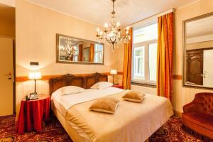 ein Schlafzimmer mit einem Bett, einem Spiegel und einem Stuhl in der Unterkunft Avenue Hotel by F-Hotels in Blankenberge