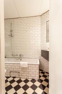 ein weiß gefliestes Badezimmer mit Badewanne und Waschbecken in der Unterkunft Avenue Hotel by F-Hotels in Blankenberge + 39 Fotos