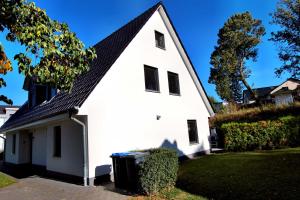 a white house with a black roof and a trash can at Ferienhaus GOLFER_S HOUSE in Göhren-Lebbin