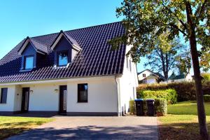 une maison blanche avec un toit noir dans l'établissement Ferienhaus GOLFER_S HOUSE, à Göhren-Lebbin