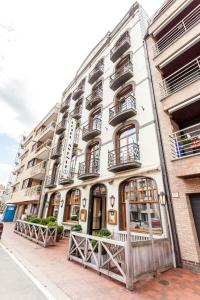 ein weißes Gebäude mit Fenstern und Balkonen auf einer Straße in der Unterkunft Avenue Hotel by F-Hotels in Blankenberge