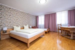 sypialnia z łóżkiem i ścianą z cegły w obiekcie Landhaus Lindner Appartements w mieście Fügen